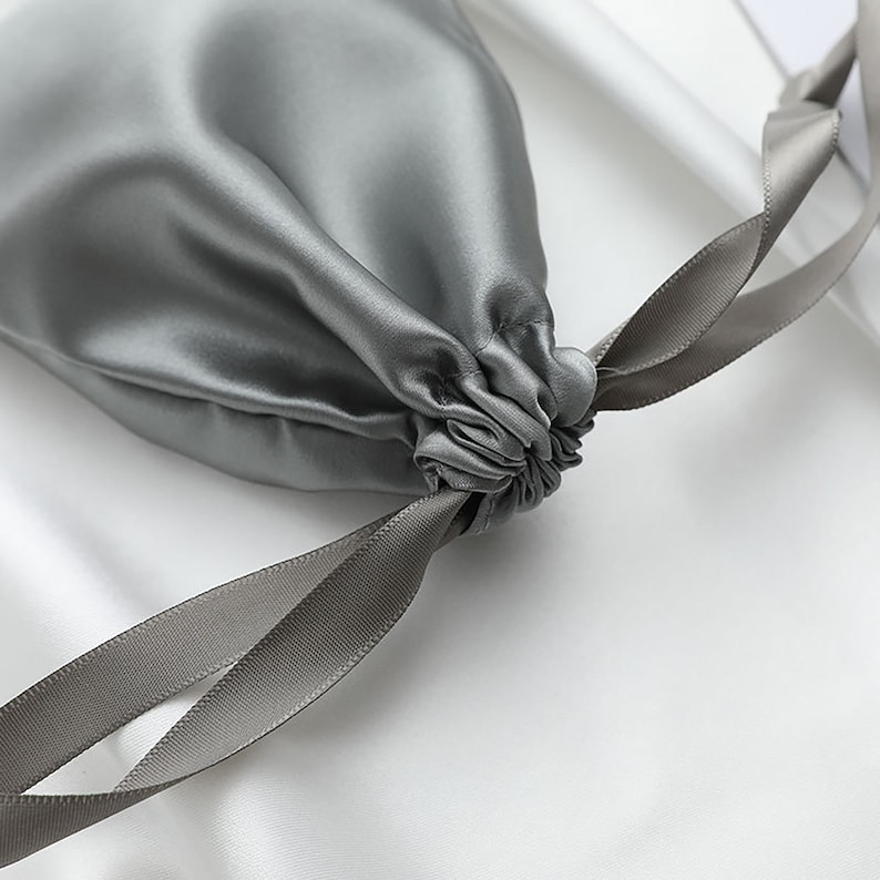 May include: A gray silk drawstring pouch with a gray satin ribbon.