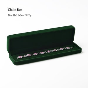 May include: A dark green velvet chain box, open to reveal a silver bracelet with pink gemstones. The box is rectangular and measures 22cm long, 5.6cm wide, and 3cm high. The text "Chain Box" is visible.