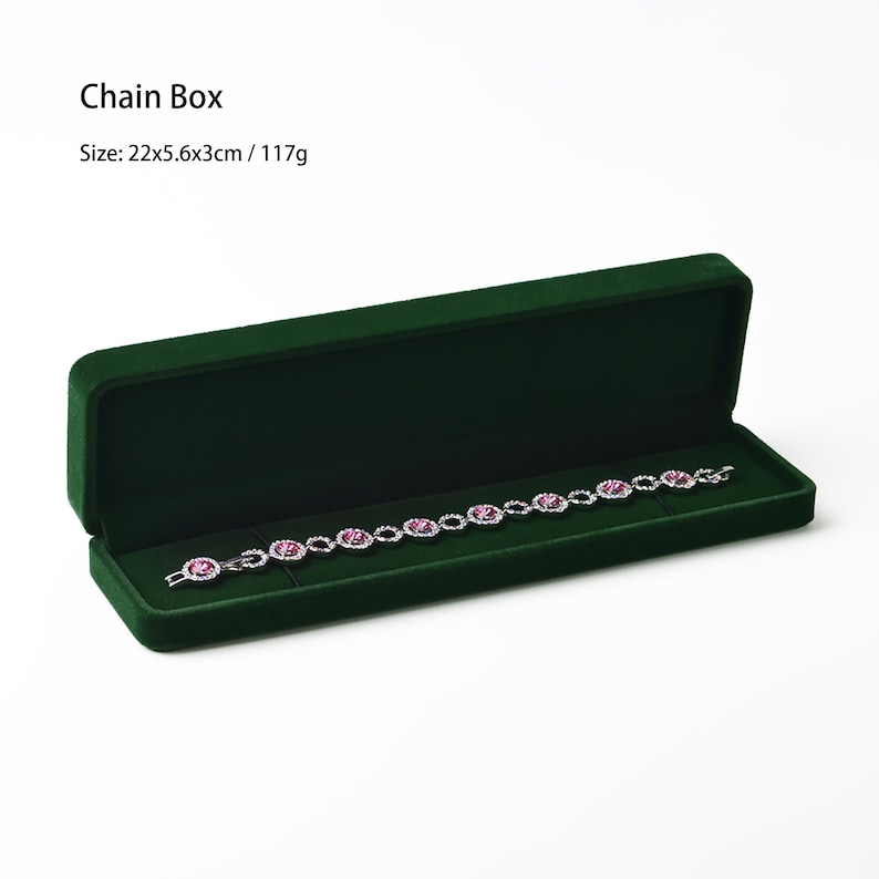 May include: A dark green velvet chain box, open to reveal a silver bracelet with pink gemstones. The box is rectangular and measures 22cm long, 5.6cm wide, and 3cm high. The text "Chain Box" is visible.