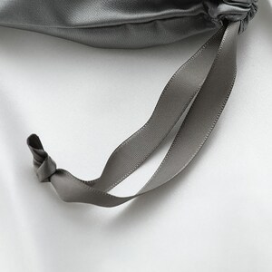 May include: A gray satin drawstring bag with a gray satin ribbon.