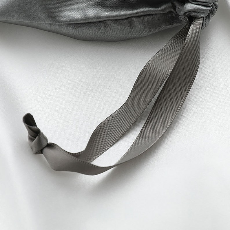May include: A gray satin drawstring bag with a gray satin ribbon.