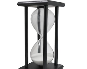 May include: A black wooden hourglass with a clear glass bulb and white sand. The hourglass is about 6 inches tall.