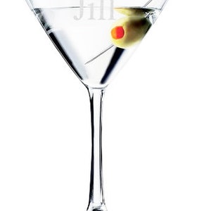 Puede incluir: Una copa de martini de vidrio transparente con una aceituna verde y un palillo de c&oacute;ctel. La copa est&aacute; grabada con el nombre "Jill".