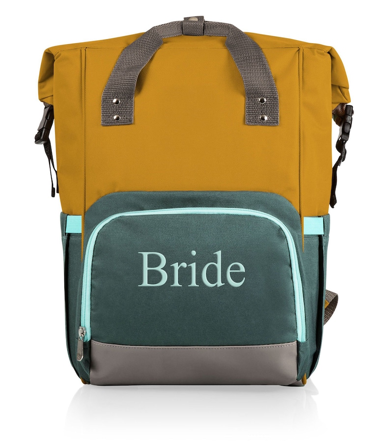 May include: A mustard yellow and teal backpack with the word "Bride" embroidered on the front. The backpack has a grey handle and straps, a teal zip, and a grey bottom panel. It features a roll-top design with side buckles.