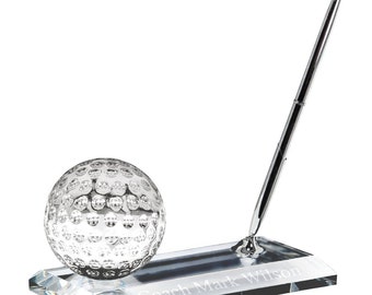 May include: Crystal golf ball desk set with a silver pen and a clear base engraved with "Coach Mark Wilson".