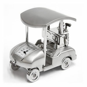 May include: A silver golf cart clock with a black face and white hands. The clock has a black canopy and a silver golf club on the back.