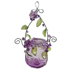 Pu&ograve; includere: Un portacandele sospeso in vetro con una tonalit&agrave; viola. Il supporto &egrave; decorato con fiori viola, foglie verdi e perline trasparenti. La struttura metallica presenta un design a spirale decorativo.