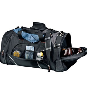 Puede incluir: Bolsa de viaje de lona negra con m&uacute;ltiples bolsillos y un compartimento para zapatos. La bolsa est&aacute; abierta y muestra una toalla azul, gafas de sol, un mando a distancia y un peque&ntilde;o recipiente de bet&uacute;n para zapatos en el interior.
