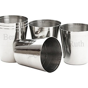 May include: Six silver metal cups, some stacked on top of each other. The cups are smooth and shiny.