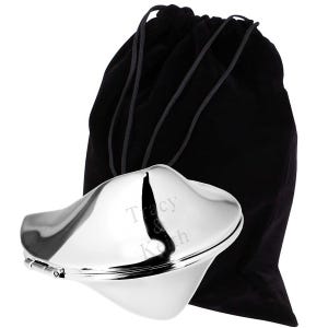 May include: A silver-colored fortune cookie-shaped container with the names "Tracy & Keith" engraved on the front. It is paired with a black drawstring bag. The container has a hinged opening.