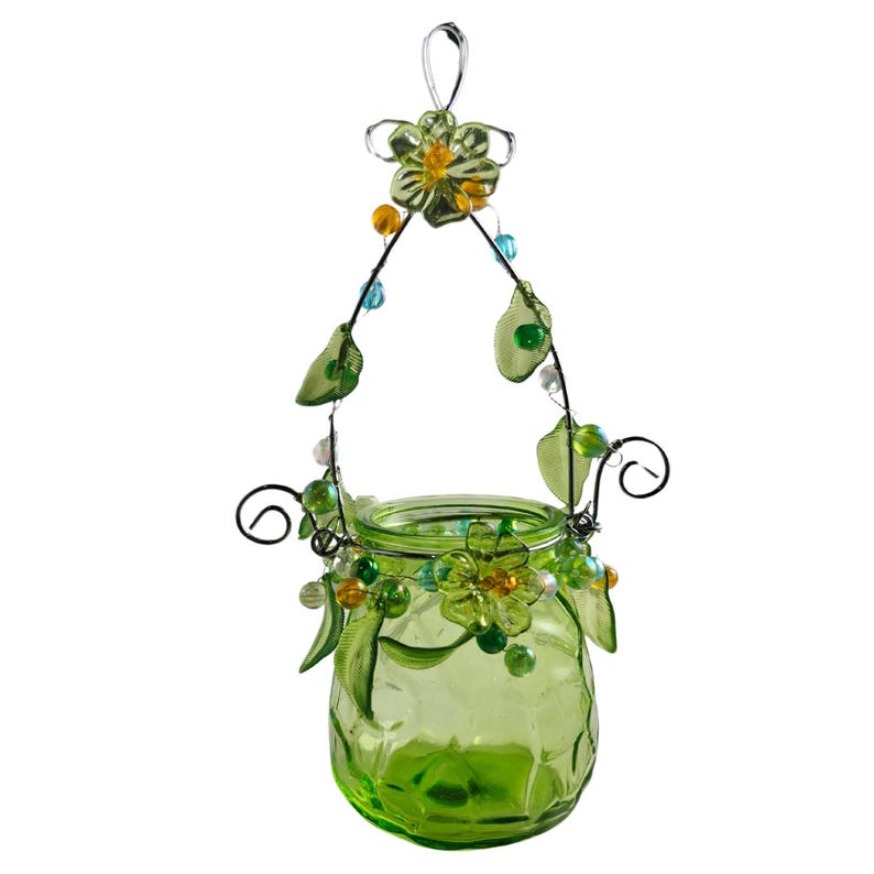Pu&ograve; includere: Un portacandele sospeso in vetro verde con una struttura in filo metallico. La cornice &egrave; decorata con foglie verdi, fiori e perline colorate. Il portacandele ha un manico per appenderlo ed &egrave; progettato per contenere una piccola candela.