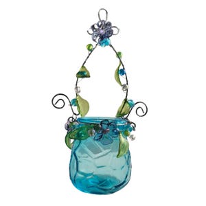 Pu&ograve; includere: Un barattolo di vetro turchese sospeso con un manico decorativo in filo di ferro. Il barattolo &egrave; adornato con fiori blu, foglie verdi e perline. Il manico in filo di ferro &egrave; impreziosito da perline verdi e blu e un fiore in cima.