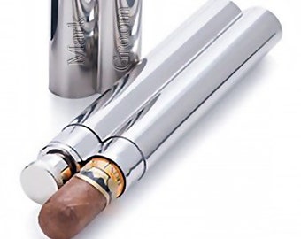 May include: A polished silver cigar case with a matching lid. The case is cylindrical with a double-barrel design, and a cigar is partially visible inside. The lid is engraved with the words "Mark Groom".