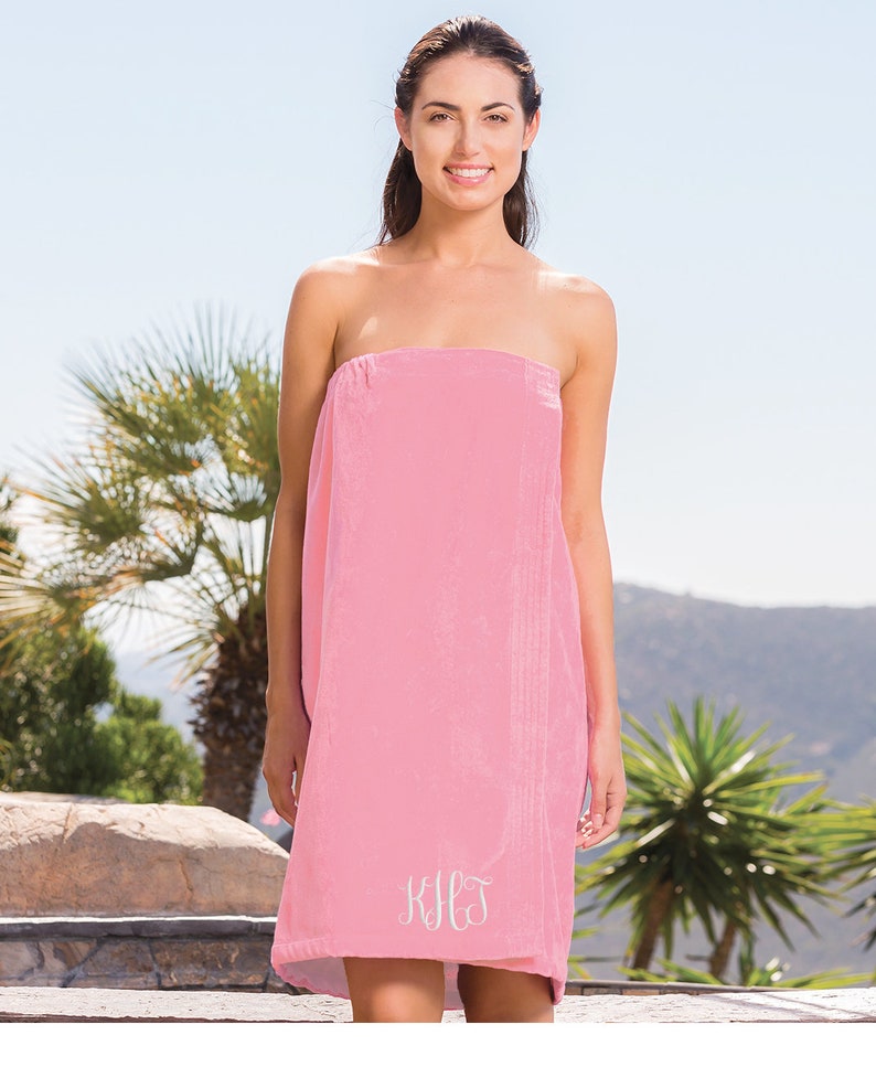 May include: Pink wrap towel with a white monogram "K.H.J." embroidered on the front.