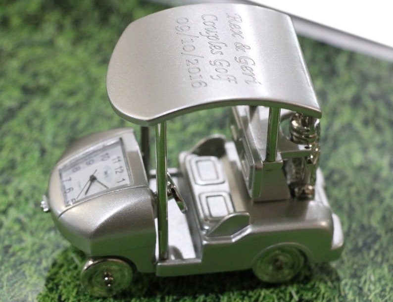 May include: Silver golf cart clock with a personalized inscription that reads "Rex & Geri Couples Golf 09/10/2016".