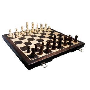 May include: A wooden chess set with a dark brown frame and a checkered playing surface. The chess pieces are arranged on the board, with light-colored pieces on one side and dark brown pieces on the other. The set includes a folding board.