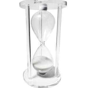 May include: A clear glass hourglass with white sand, set on a clear acrylic base with two vertical supports.