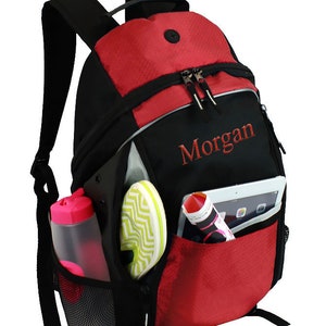 May include: A red and black backpack with a zippered pocket and a mesh side pocket. The backpack has a name embroidered on the front: "Morgan".