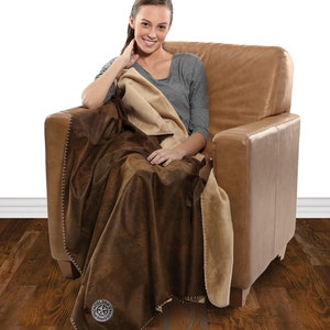 May include: A brown and tan fleece throw blanket with a stitched edge and a circular logo featuring a star and the text "Colone" and "Dallas, Texas".