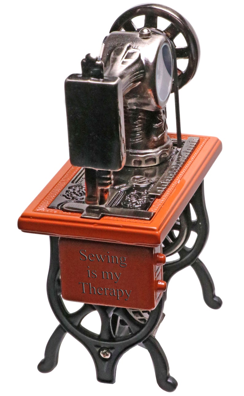 Peut inclure: Une petite figurine de machine &agrave; coudre rouge et noire avec les mots "Sewing is my Therapy" sur le devant.