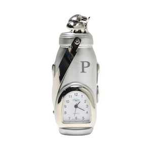 May include: Silver golf bag shaped desk clock with a white face and black hands. The clock has a quartz movement and is personalized with the letter "P".