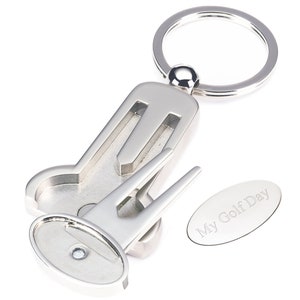 May include: Silver golf ball marker keychain with a divot tool and a bottle opener. The keychain has a ring for attaching to keys and an oval tag that says "My Golf Day".