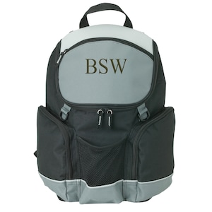 May include: A black and gray backpack with the initials "BSW" embroidered on the front. The backpack has a top handle, side pockets, and a mesh front pocket. The bottom and top sections are gray, while the main body is black.