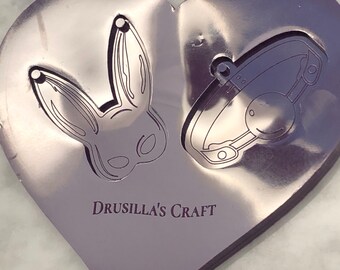 May include: A purple heart-shaped silicone mold with two designs: a bunny mask and a collar with a ball. The mold is labeled "Drusilla's Craft".