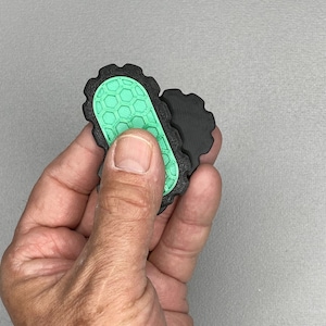 May include: Two black and green textured oval-shaped objects with a honeycomb pattern.