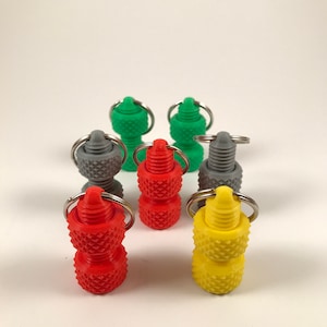 May include: Six small keychains with different colored tops. The keychains are made of metal and plastic. The tops are red, yellow, green, and gray.