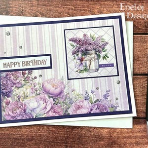 May include: A handmade birthday card with a floral design. The card features a purple and white striped background, a square image of a mason jar filled with purple flowers, and the words "HAPPY BIRTHDAY". A black pen rests on the side.