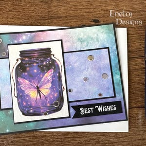 May include: A greeting card with a galaxy design featuring a mason jar with a glowing butterfly inside. The card has the text "Best Wishes" on the front.