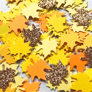 May include: Assortment of yellow, orange, and gold glitter confetti in the shape of maple leaves.