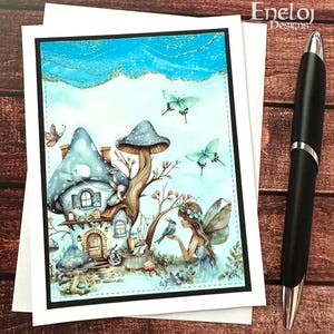 May include: A greeting card featuring a whimsical illustration of a fairy house with a mushroom roof, butterflies, and a fairy. The card has a black border and is on a white background. A black pen is on the right side of the card. The text "Eneloj Designs" is in the upper right corner.