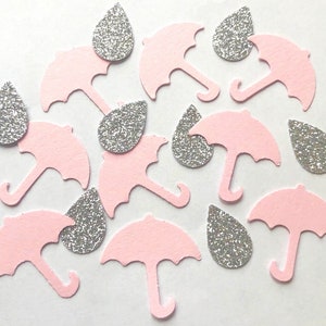 Op de afbeelding: Roze en zilveren confetti met een regenmotief. De confetti heeft kleine regendruppels en paraplu's.