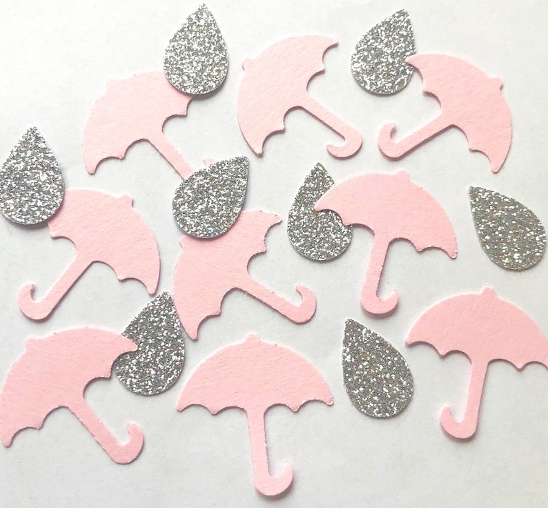 Op de afbeelding: Roze en zilveren confetti met een regenmotief. De confetti heeft kleine regendruppels en paraplu's.