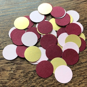 May include: A pile of confetti circles in burgundy, gold, and pink.