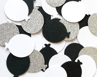 May include: Black, white, and silver glitter confetti in the shape of balloons. The confetti is perfect for adding a festive touch to any party or celebration.
