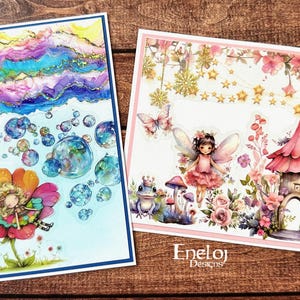 May include: Two whimsical art prints. One features a fairy on a flower with bubbles and a colorful sky. The other depicts a fairy, a mushroom house, and floral elements. Both have a white border and the "Eneloj Designs" logo.