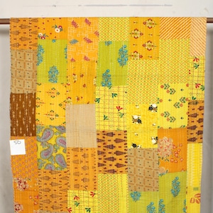 Może przedstawiać: Żółta kołdra kantha z patchworkowym wzorem. Kołdra składa się z wielu różnych kwadratów tkaniny, z których każdy ma inny wzór. Kołdra jest pięknym przykładem tradycyjnego rzemiosła indyjskiego.