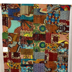 May include: A colourful patchwork quilt featuring a range of patterns and colours, including red, blue, green, yellow, and brown. The quilt is made from fabric scraps sewn together in a random design. The quilt is hand-stitched and has a unique, handmade appearance.