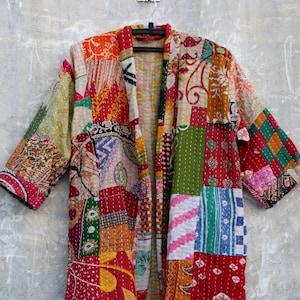 Puede incluir: Una chaqueta acolchada de patchwork colorida con estilo kimono. La chaqueta está hecha de varias telas en tonos de rojo, verde, azul y amarillo.