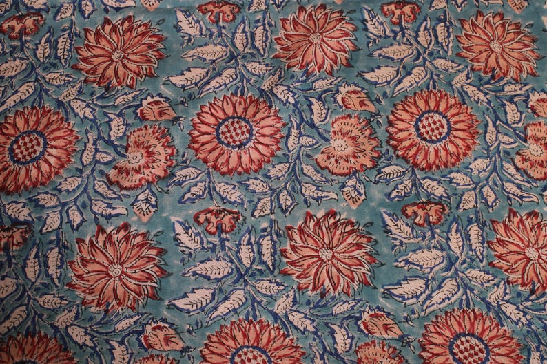 May include: A fabric featuring a repeating floral pattern. Large, stylised flowers in coral and peach tones are set against a teal background. Blue and white leaf details complete the vibrant textile design.