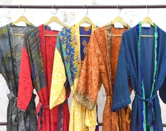 May include: Six colorful silk robes hang on hangers. The robes are made of different fabrics and patterns, including floral, paisley, and geometric designs. The robes are all in various shades of blue, green, yellow, orange, and red.