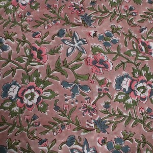 May include: A fabric featuring a floral pattern with pink, white, and blue flowers and green leaves on a dusty rose background. The design includes stylized blooms and winding vines, creating a classic, botanical aesthetic.