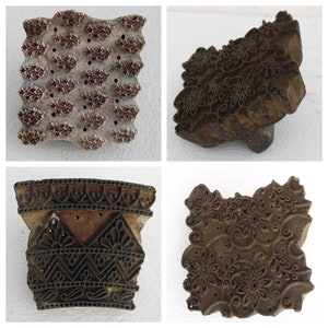 May include: Four vintage wooden printing blocks with intricate floral and geometric designs. The blocks are made of dark brown wood and have been used to create patterns on fabric.