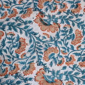 May include: White fabric with a repeating floral pattern. The design features large, stylized flowers in shades of peach and teal, with teal leaves and stems. The overall effect is a detailed, decorative textile.
