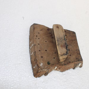May include: A wooden printing block with a handle. The block has a rectangular shape and is covered in small holes. The handle is made of wood and is attached to the block.