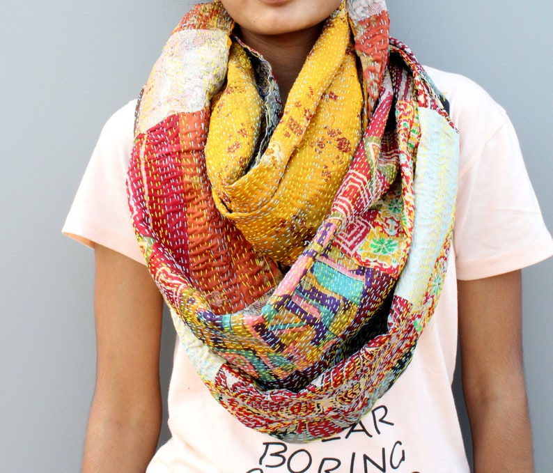 May include: A colourful patchwork scarf made from recycled saris. The scarf is a mix of red, yellow, blue, green and white fabrics. It is a unique and stylish accessory.