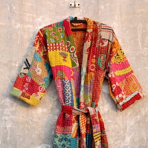 May include: A colorful patchwork kimono robe with a tie belt. The robe is made of various fabrics in shades of red, pink, yellow, blue, green, and brown. The fabric is quilted and has a vintage look.